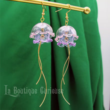 Load image into Gallery viewer, Boucles d&#39;oreilles méduse pendantes dorées en verre et acier couleur rose violet vert. Thème steampunk mer Jules Verne plongée sous marine