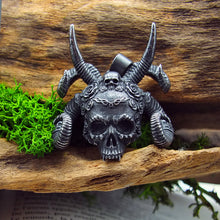 Charger l'image dans la galerie, Pendentif crâne gothique démoniaque en acier inoxydable noir avec cornes sculptées et couronne de fleurs, posé sur du bois et entouré de mousse.