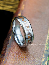 Laden Sie das Bild in den Galerie-Viewer, Bague Viking en tungstène avec runes Futhark et insert en bois, posée sur un ancien livre.
