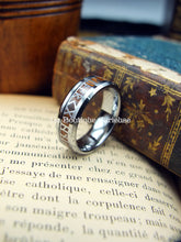 Laden Sie das Bild in den Galerie-Viewer, Bague runique Futhark en tungstène avec insert en bois, mise en scène sur un décor vintage.